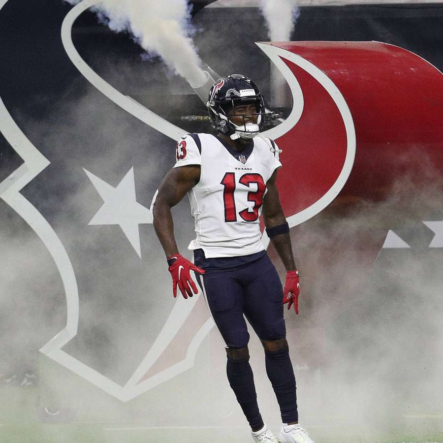 Football player wearing Texans jersey number 13 walking through smoke on field. — Brandin Cooks Wallpaper