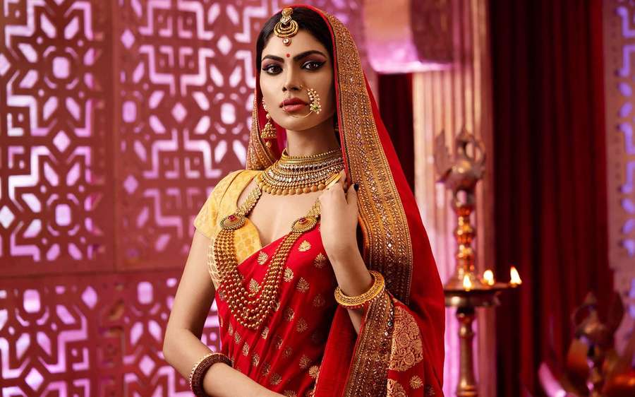 Woman in red and gold traditional Indian attire with jewelry and candles. — Bridal Background