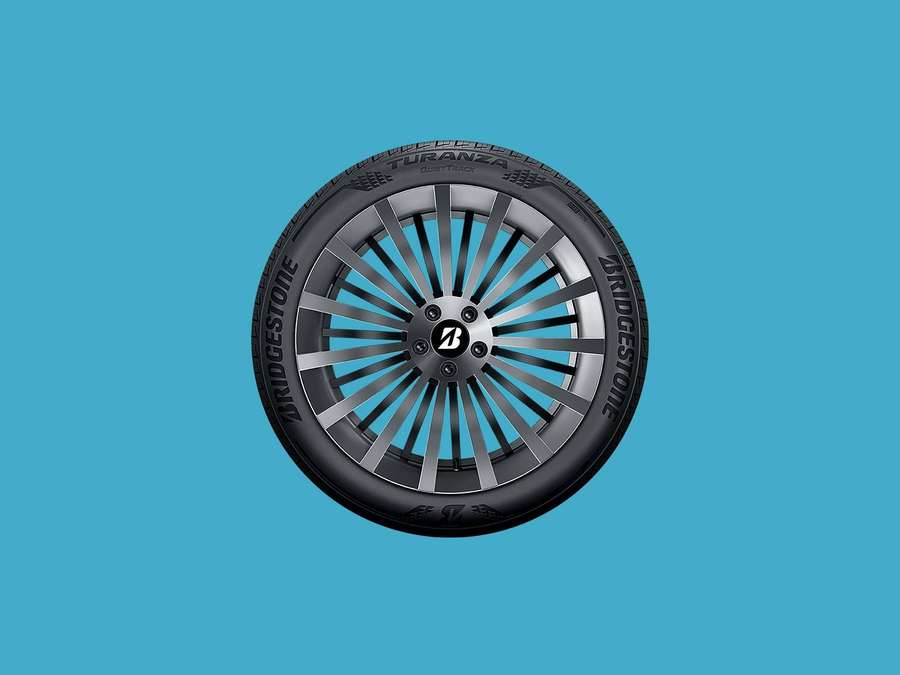 Close-up of a Bridgestone Turanza tire with silver rim on turquoise background. — Bridgestone Background