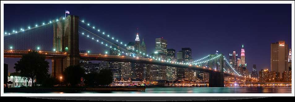 Brooklyn Bridge lit up at night over a river with city lights behind it. — Brooklyn PNG