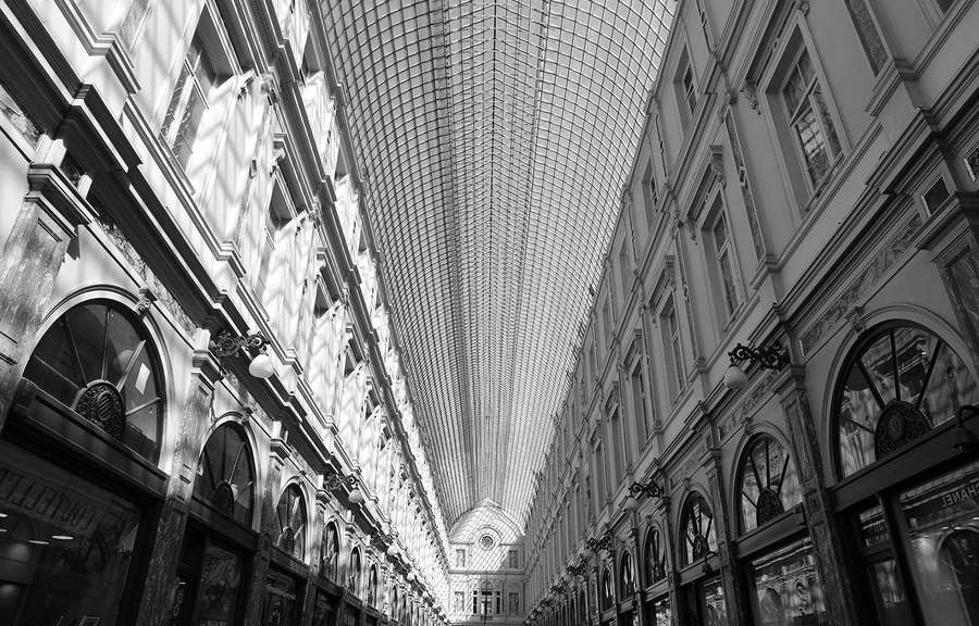 Grand glass-roofed arcade with ornate buildings on both sides. — Brussels Background