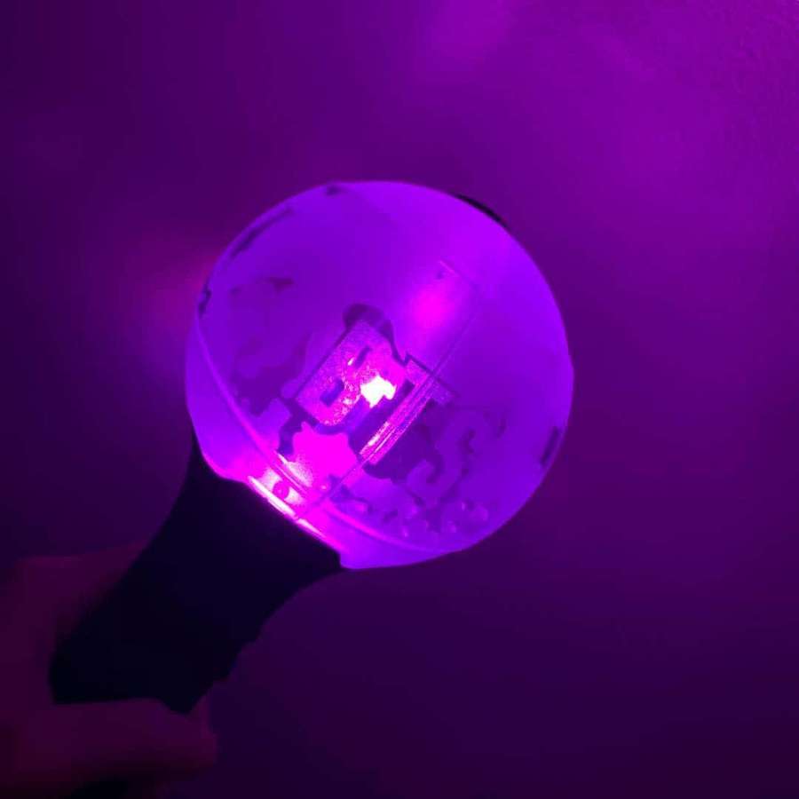 Hand holding a glowing purple LED light stick in a dark room. — Bts Army Bomb Wallpaper