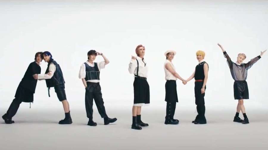 Sieben stilvolle Männer in schwarz-weißen Outfits posieren dynamisch in einem Studio. — Bts Butter Bilder