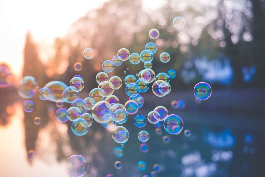 Floating soap bubbles catching sunset light in a serene outdoor scene. — Bubble Picture