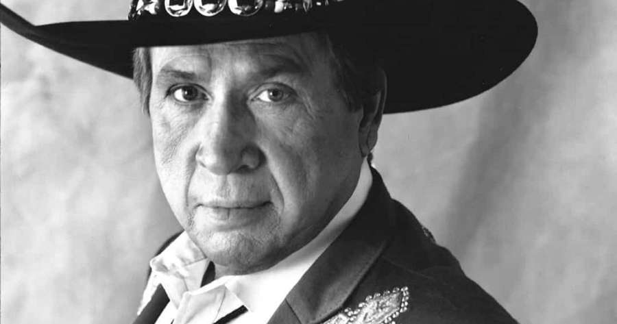 Man in ornate hat and jacket looking directly at viewer in black and white studio portrait. — Buck Owens Wallpaper