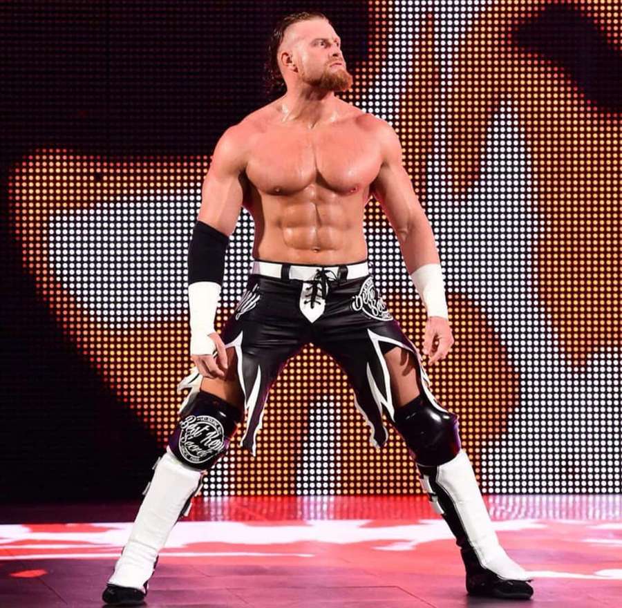 Wrestler in black and white gear posing on a lit stage. — Buddy Murphy Wallpaper