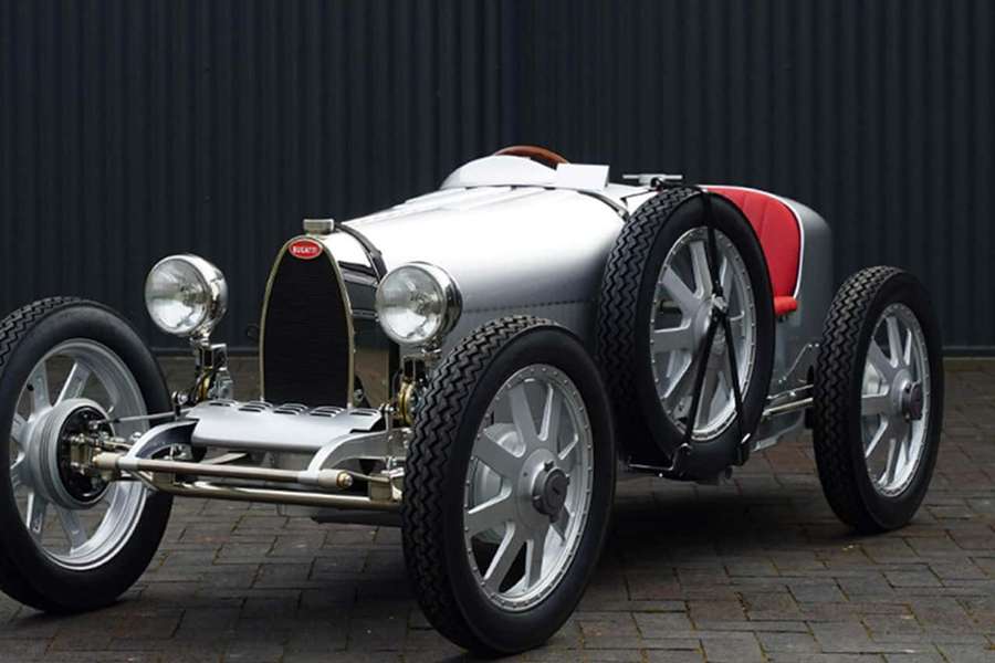 Silver vintage Bugatti race car with red seat and exposed wheels on brick pavement. — Bugatti Type 35 Wallpaper
