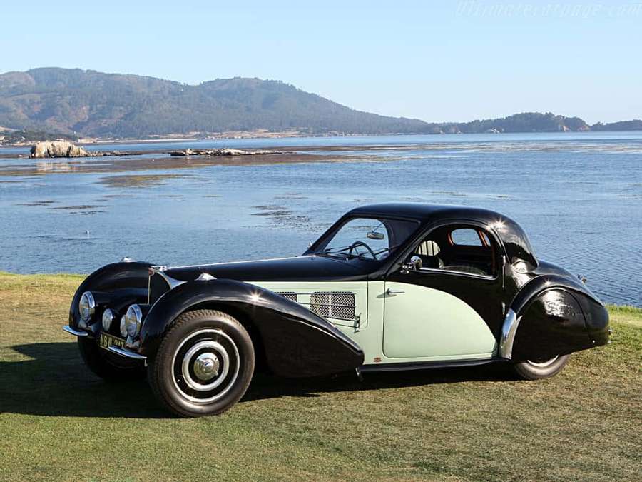 Vintage musta ja mintunvihreä urheiluauto pysäköitynä ruoholle veden lähelle, taustalla kukkuloita. — Bugatti Type 57 Taustakuvat