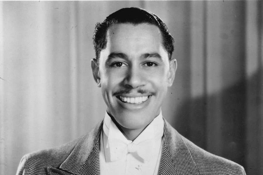A smiling man in a suit and bow tie poses for a studio portrait. — Cab Calloway Wallpaper