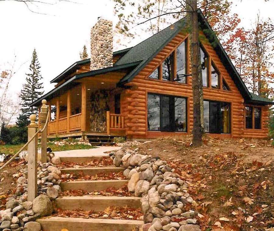 Rustic log cabin with stone chimney surrounded by autumn trees and fallen leaves. — Cabin Picture