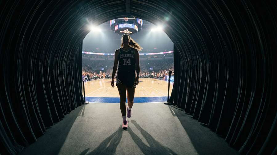 Caitlin Clark walking through tunnel onto court, silhouette against bright lights, cinematic. — Caitlin Clark Wallpaper