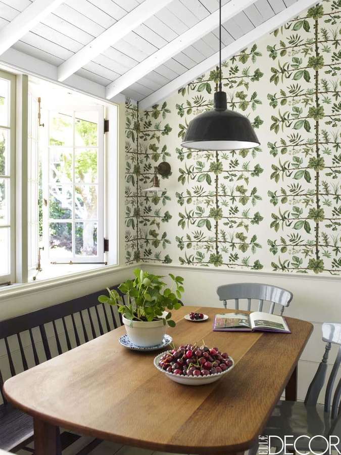Mesa de madeira para jantar com cerejas e planta sob pendente perto da janela com papel de parede botânico. — Calma Papéis de Parede