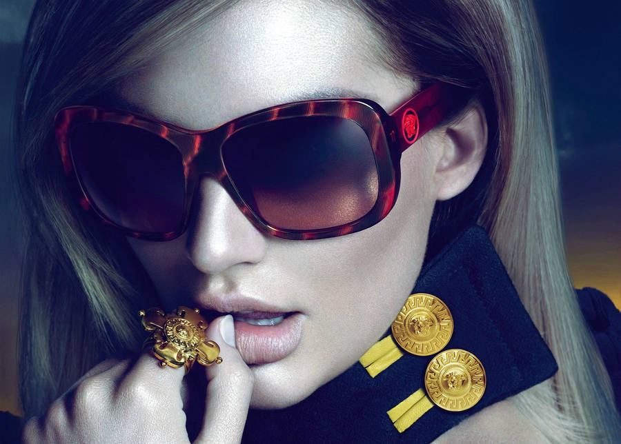 A stylish woman in red sunglasses and gold accessories poses with a confident expression. — Candice Background