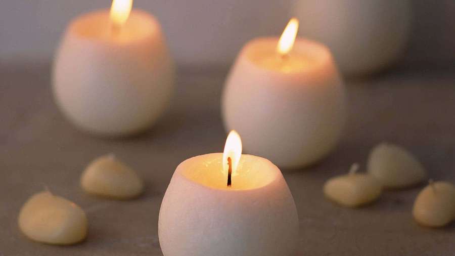 Three lit white candles with wax droplets on a neutral surface. — Candles Wallpaper