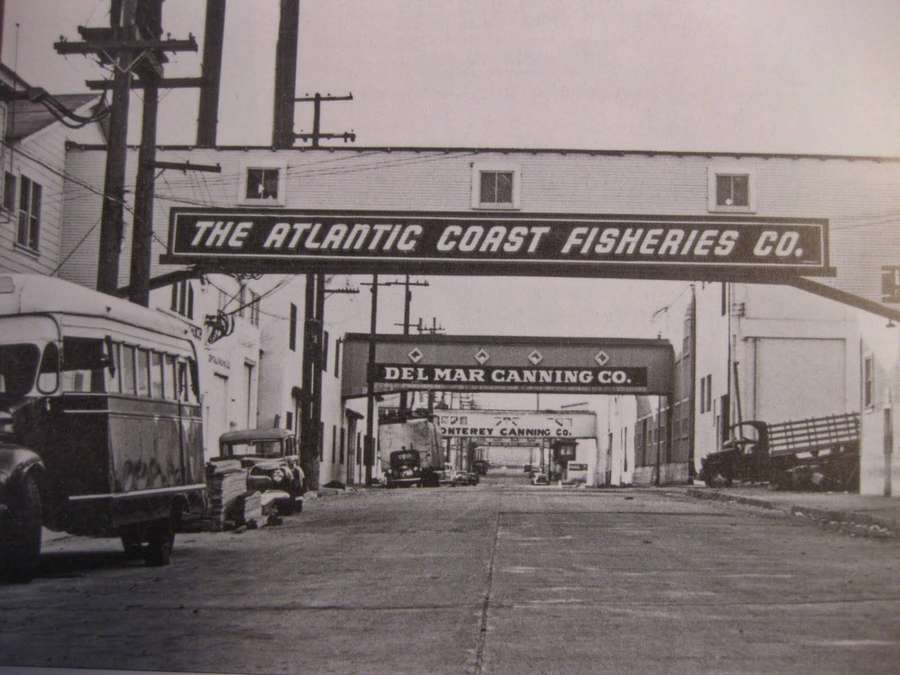 Vintage-Lastwagen unter Fabrikschildern von Konserven- und Fischereiunternehmen geparkt. — Cannery Row Bilder