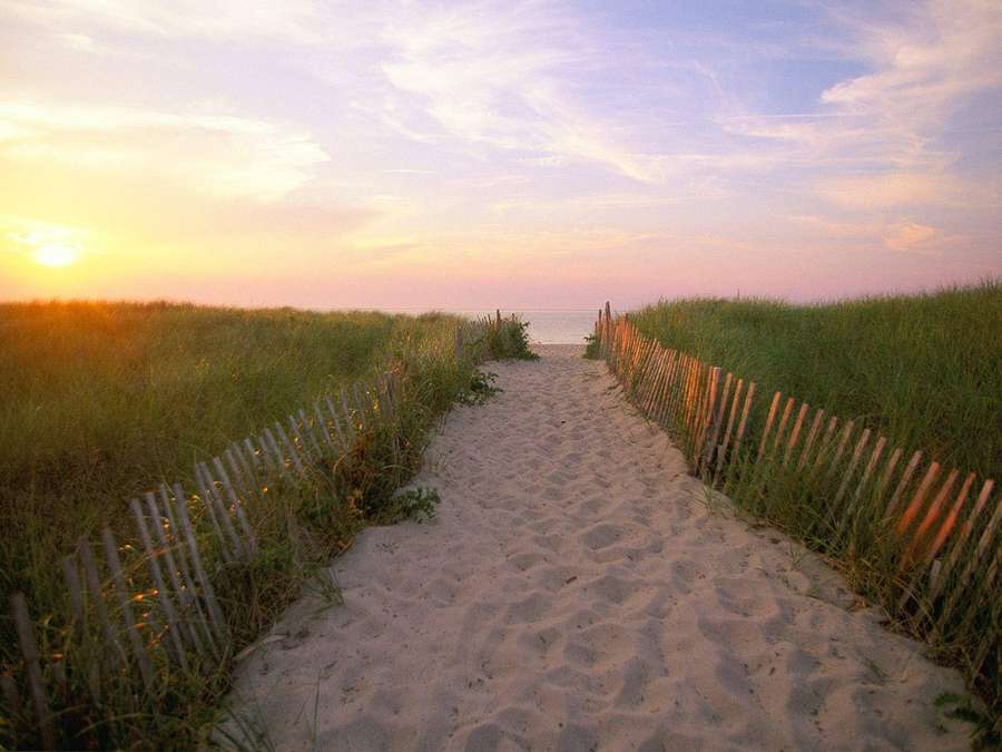 Sandstrandweg mit Holzzäunen, der bei Sonnenuntergang zum Ozean führt — Cape Cod Bilder