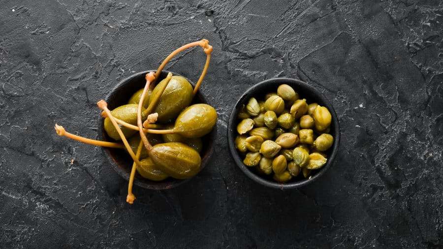 Two bowls of green capers on a dark stone surface. — Capers Wallpaper