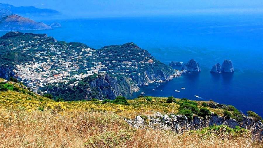 Küstenstadt auf Klippen mit blauem Meer und Felsformationen — Capri, Italien Wallpaper