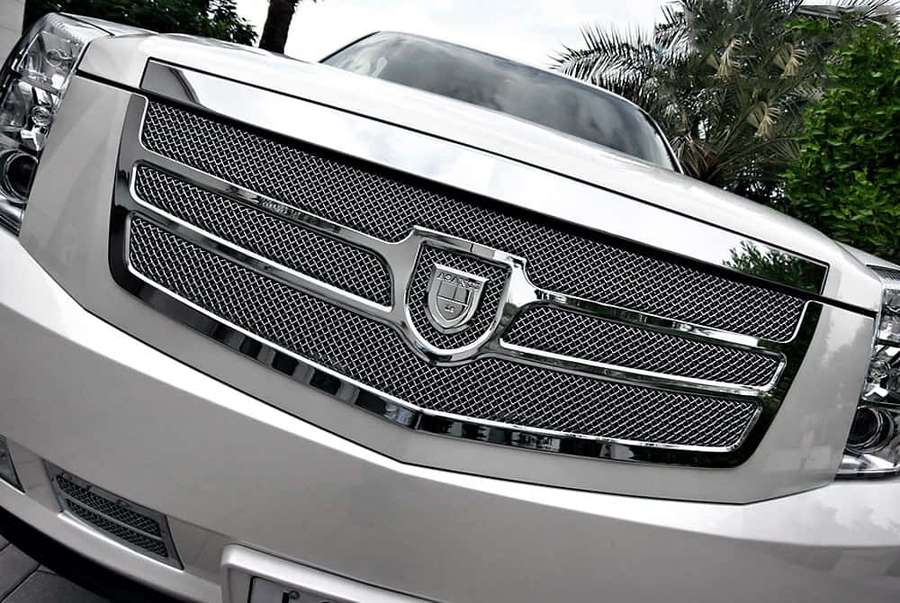 Close-up of a white luxury SUV's chrome grille with palm tree reflection. — Car Grill Wallpaper