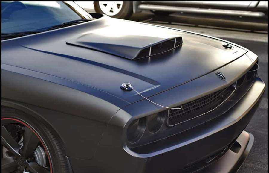Matte black muscle car with hood scoop and red wheel accents parked on street. — Car Hood Wallpaper
