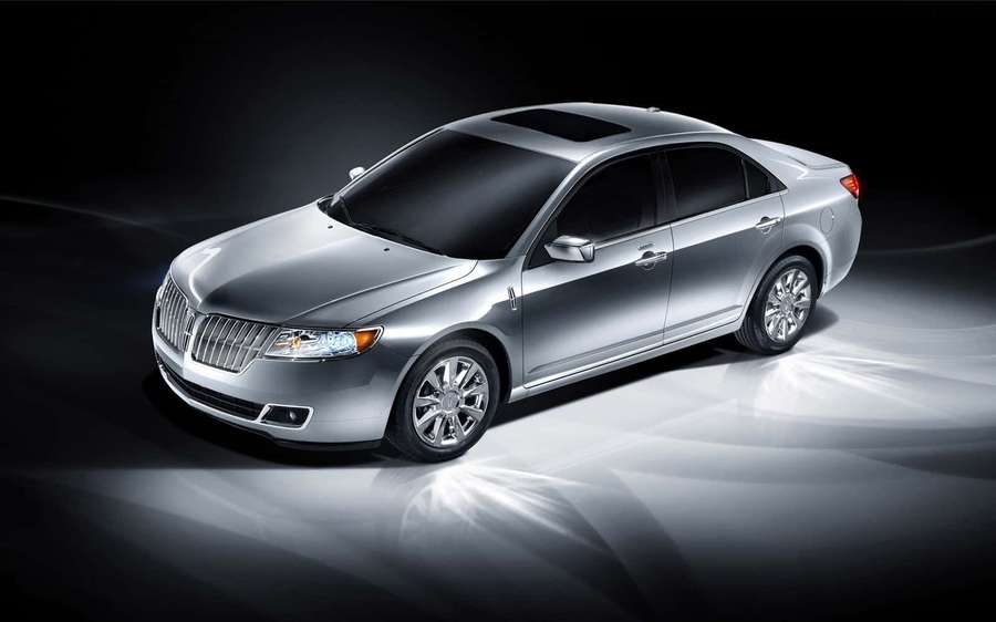 Silver luxury sedan illuminated by spotlights on a dark reflective surface. — Car Model Wallpaper