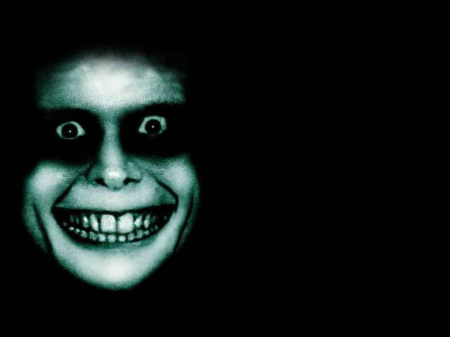 Um rosto verde pálido brilhante com olhos grandes e um sorriso largo e cheio de dentes na escuridão total. — Cara assustadora Papéis de Parede