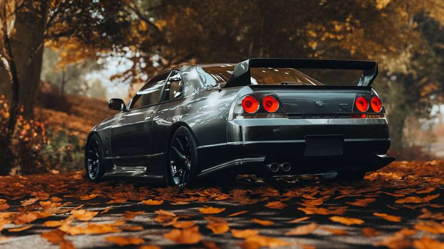 Carro esportivo preto com lanternas traseiras vermelhas estacionado em folhas de outono sob árvores. — Carro Skyline Papéis de Parede