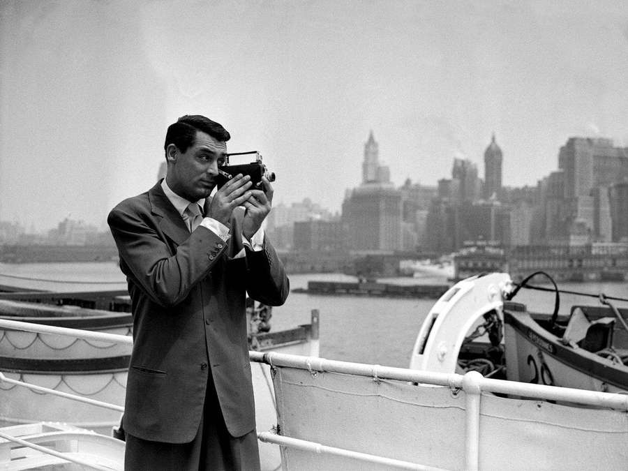 Man in suit photographing city skyline from boat — Cary grant Background