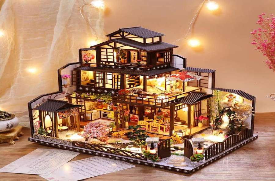 Uma miniatura detalhada de uma casa japonesa com luzes brilhantes e decoração de jardim em uma mesa de madeira. — Casa de bonecas Papéis de Parede