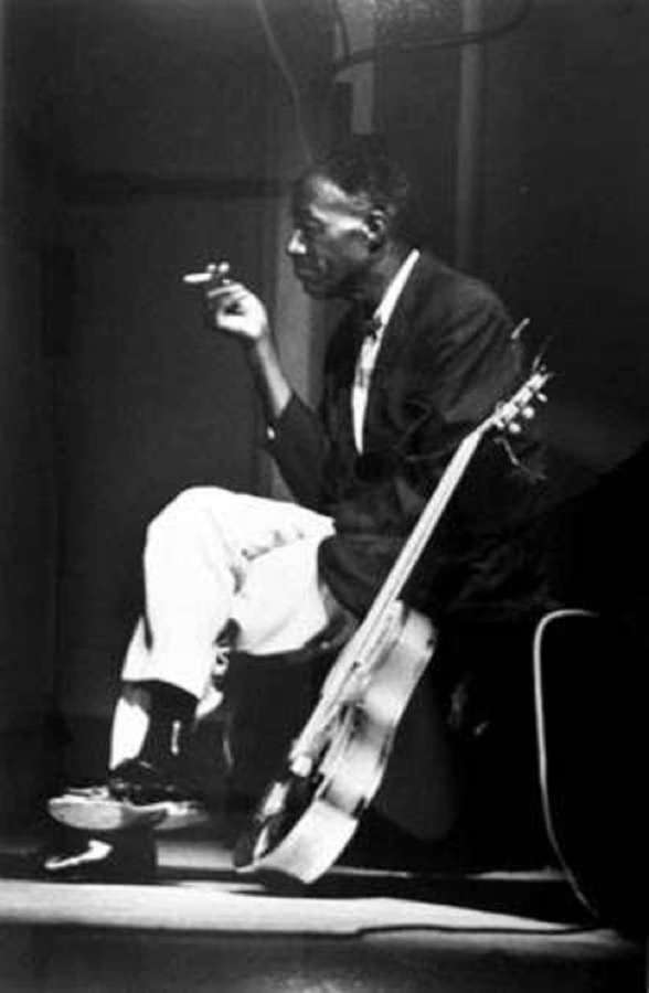 Músico de jazz segurando cigarro e contrabaixo em iluminação de estúdio fraca. — Casa Son Papéis de Parede