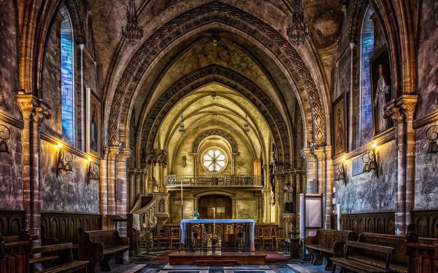 Gothic church interior with stone arches stained glass windows and wooden pews. — Catholic Wallpaper