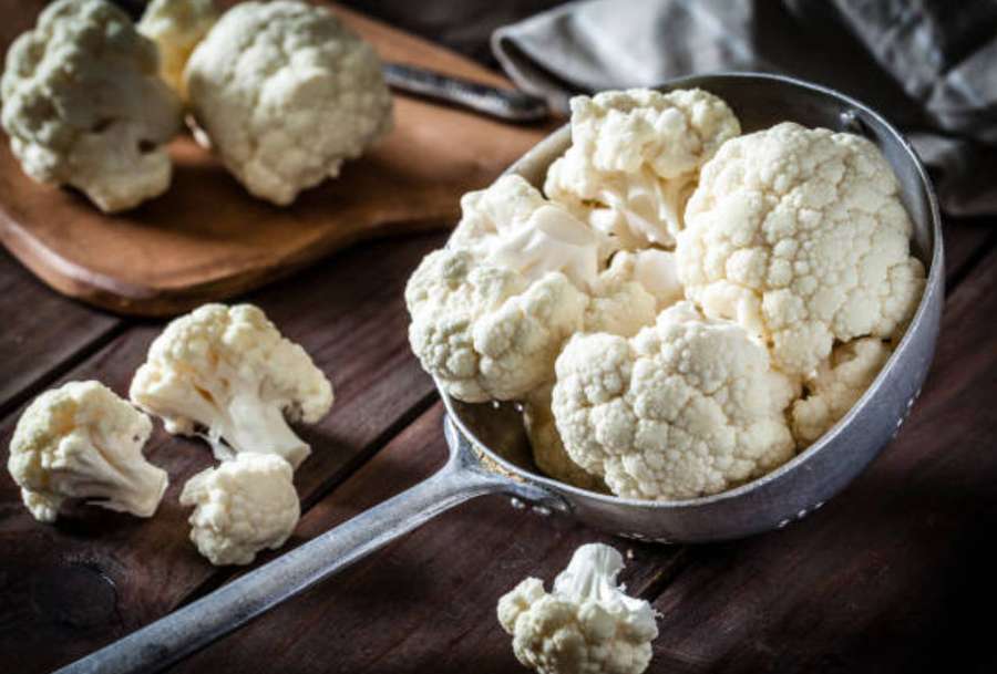 Fresh cauliflower florets in a metal scoop on a wooden table. — Cauliflower Wallpaper