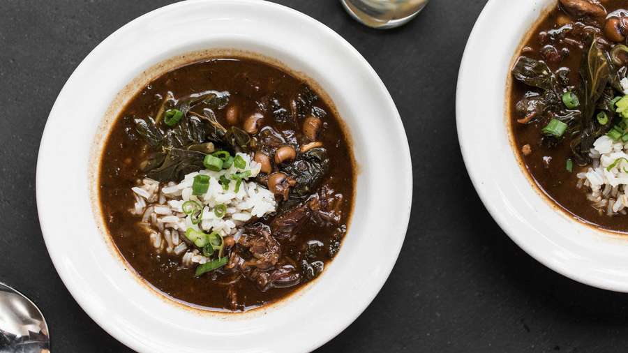 Dos tazones de gumbo con arroz y cebollas verdes en una mesa negra. — Cebolla de primavera Fondos de pantalla