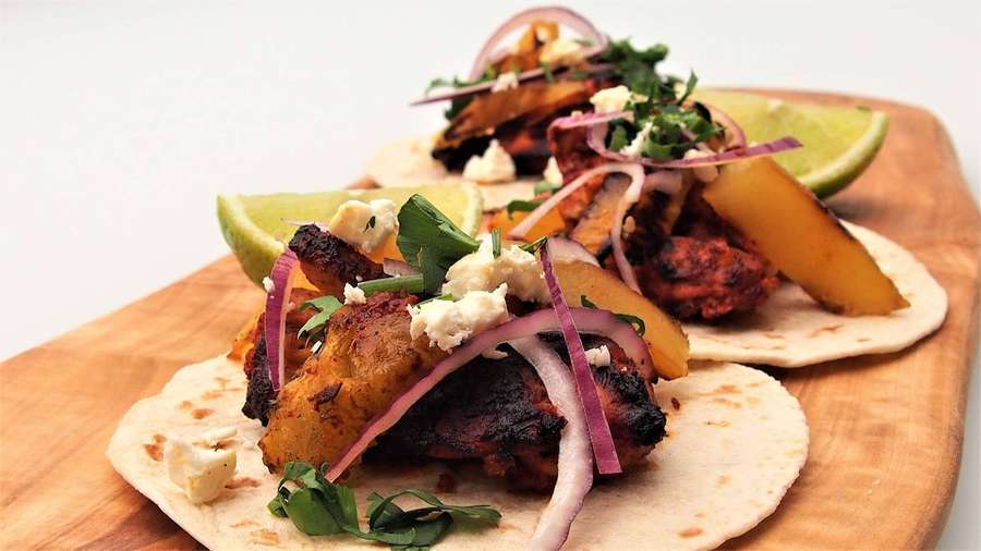 Dos tacos de pollo a la parrilla cubiertos con cebolla morada, gajos de lima y queso desmenuzado sobre una tabla de madera. — Cebolla Fondos de pantalla