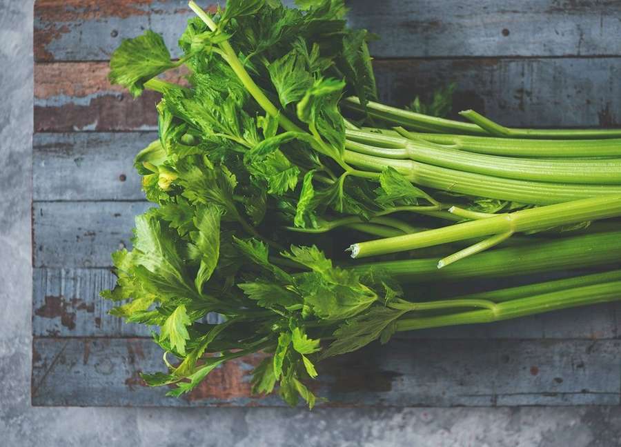 Fresh celery stalks with leaves on a rustic wooden background. — Celery Background