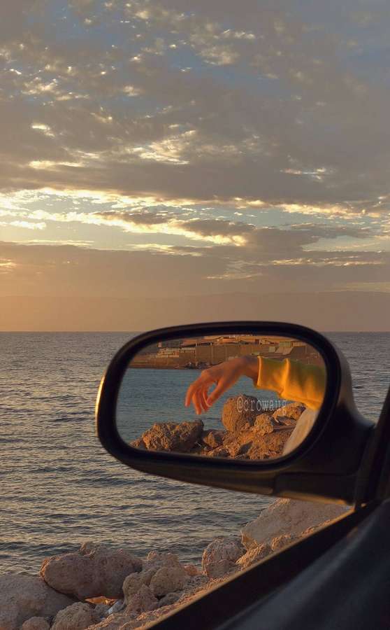 Mão alcançando o oceano através do espelho lateral do carro ao pôr do sol dourado. — Cenário iPhone Papéis de Parede
