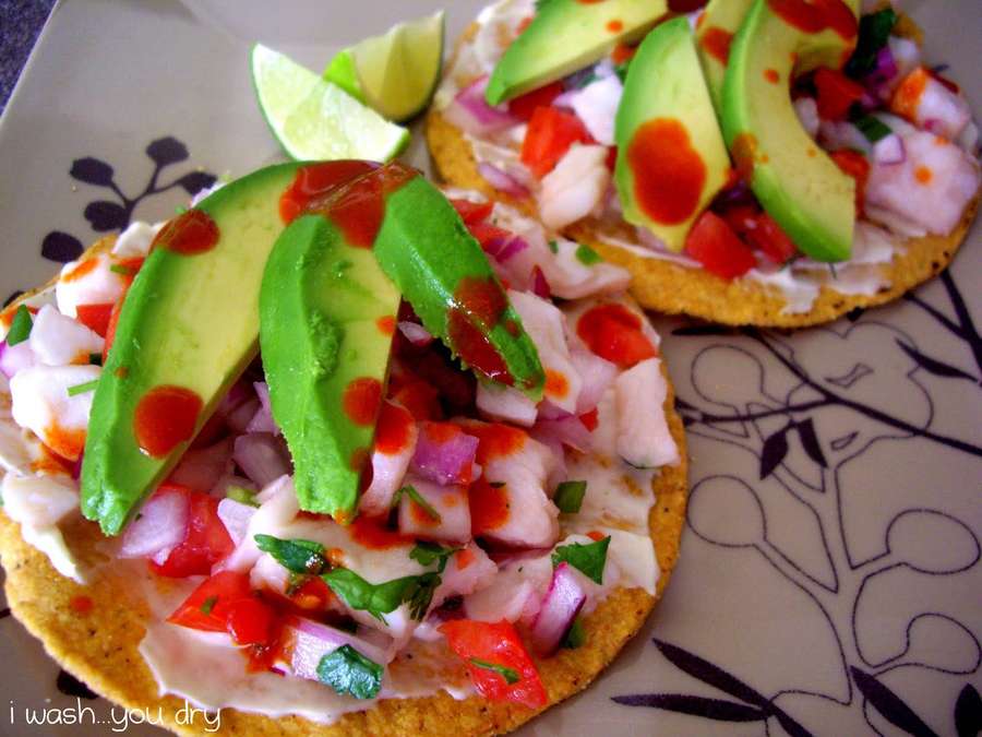 Tostadas mit Avocado-Salsa und Limettenspalten auf einem gemusterten Teller. — Ceviche Bilder