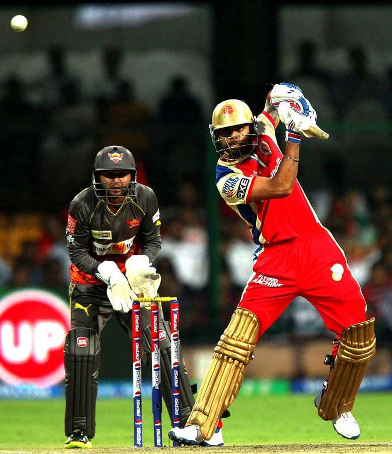Cricket batsman hitting ball with wicketkeeper ready behind stumps at night. — Challengers Wallpaper