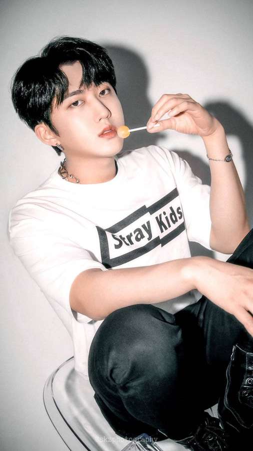 Young man holding lollipop in studio portrait — Changbin Background