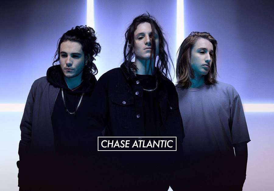 Three musicians in dark clothing under blue neon lights with Chase Atlantic text. — Chase Atlantic Wallpaper