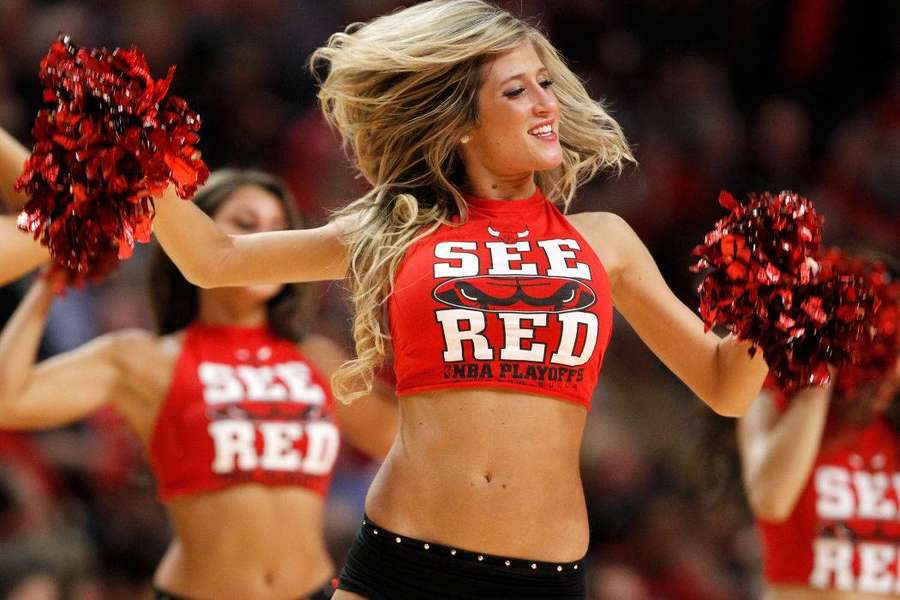 Cheerleader in red outfit dancing with pom-poms at a basketball game. — Cheerleader Wallpaper