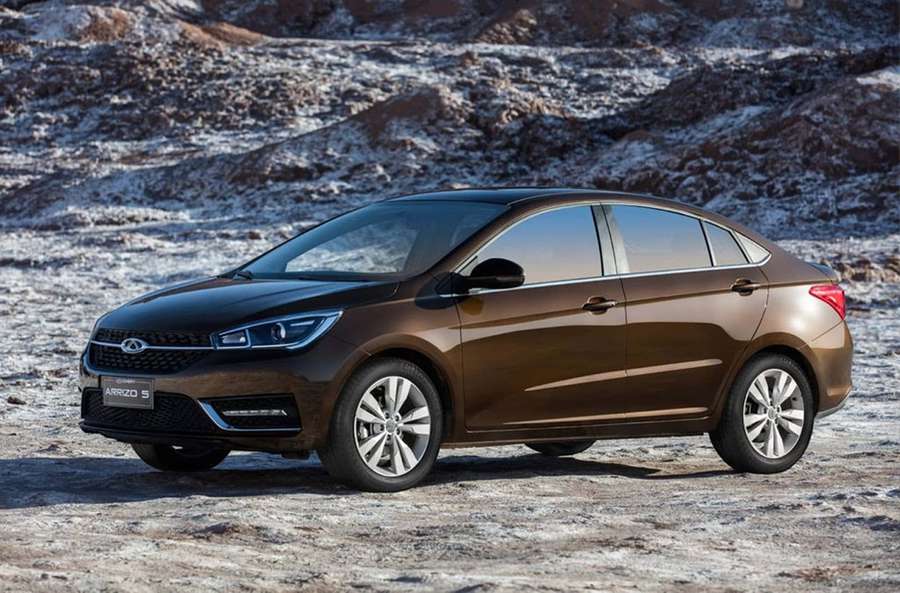 Brown sedan parked on snowy rocky terrain in daylight — Chery Wallpaper