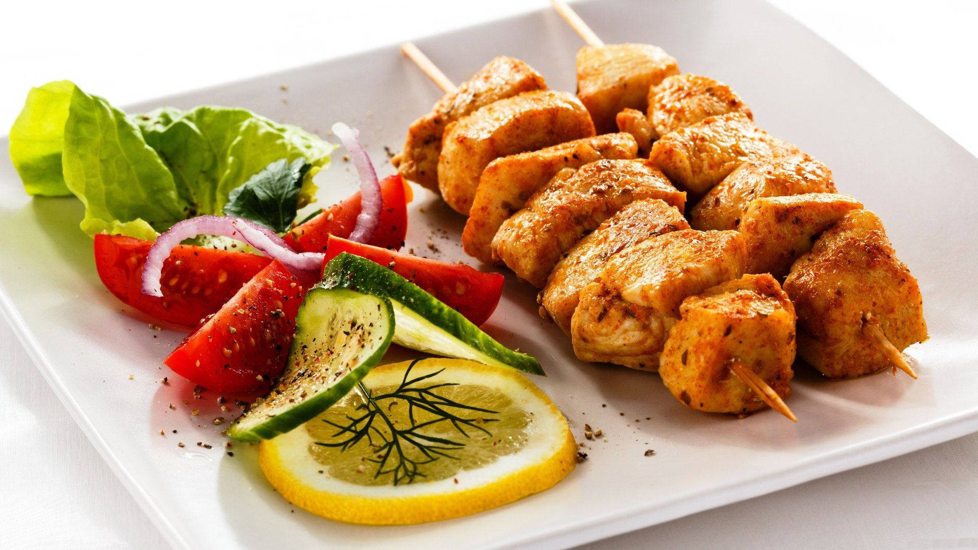 Grillade kycklingspett med färska grönsaker och citron på en vit tallrik. — Kyckling Bakgrundsbilder