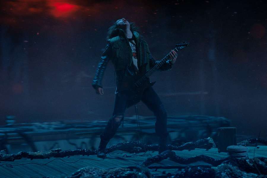Un chitarrista rock si esibisce su un palco rotto sotto luci rosse e blu. — Chitarra Sfondi