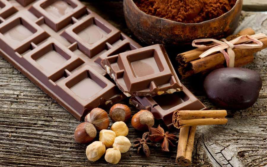 Dark chocolate bars hazelnuts and spices on a wooden surface — Chocolate Background