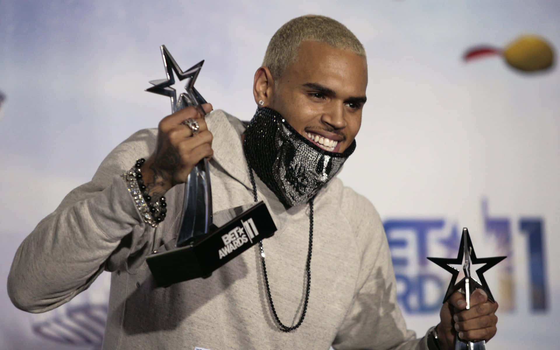 Chris Brown smiling while holding two BET Award trophies. — Chris Brown Wallpaper