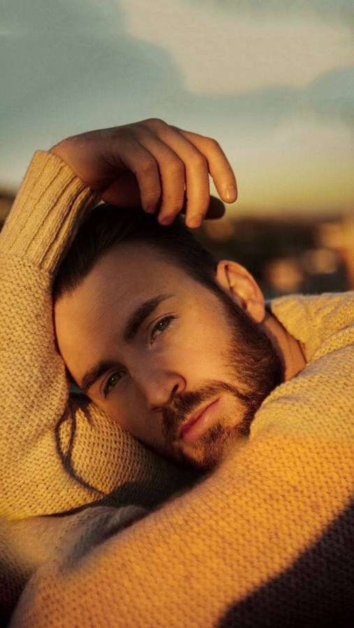 Uomo barbuto con maglione che riposa la testa durante il tramonto dorato — Chris Evans Sfondi