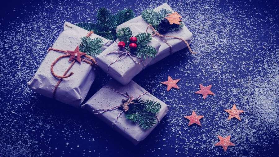 Three wrapped Christmas presents with pine and berries on snowy blue background with copper stars. — Christmas Presents Background
