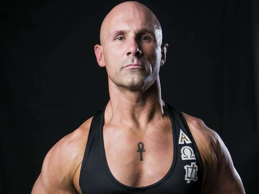 Un hombre calvo y musculoso con un tatuaje de ankh mira intensamente en un retrato de estudio. — Christopher Daniels Fondos de pantalla