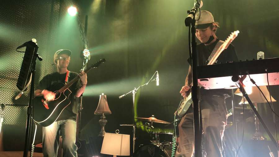 Dois músicos tocando guitarra e teclado sob luzes verdes de palco. — Cidade das Cavernas Papéis de Parede